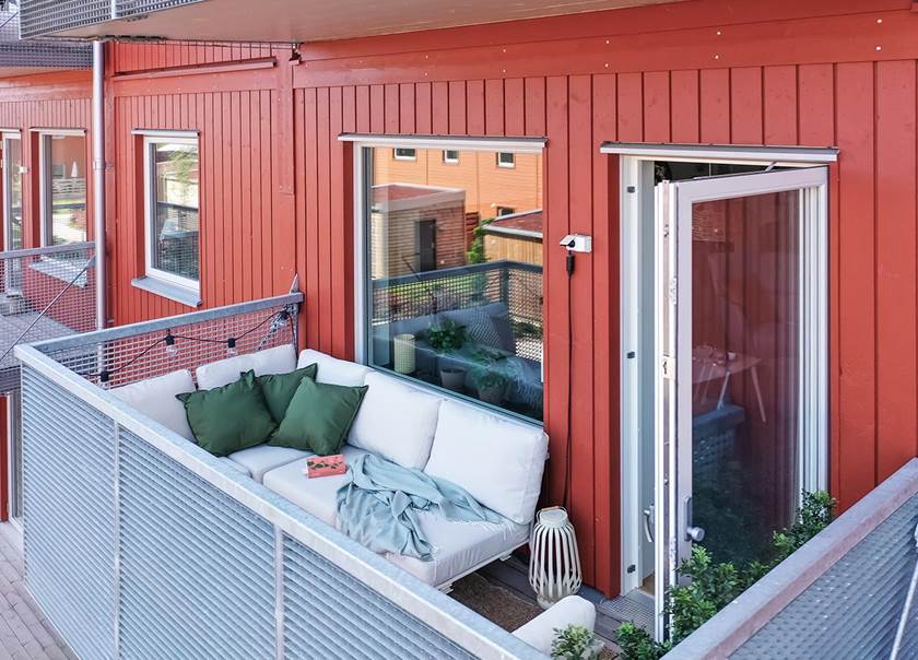 Möblerad balkong till lägenhet med röd träfasad.