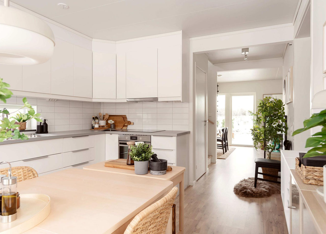 Kök med vita köksluckor och rostfria vitvaror med gång in till vardagsrum i BoKlok radhus 117 kvm