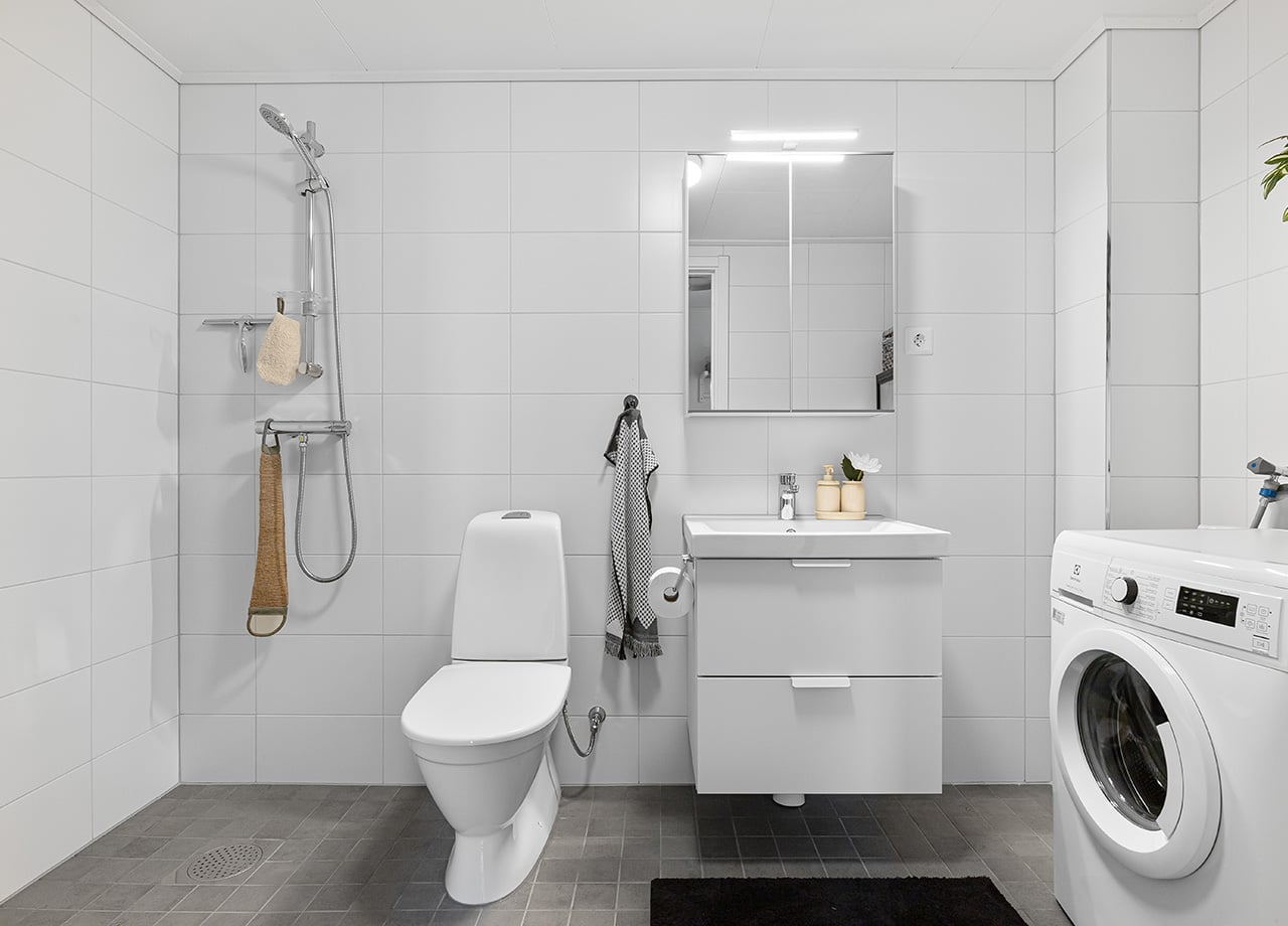 Badrum med tvättmaskin och dusch i ett BoKlok radhus.