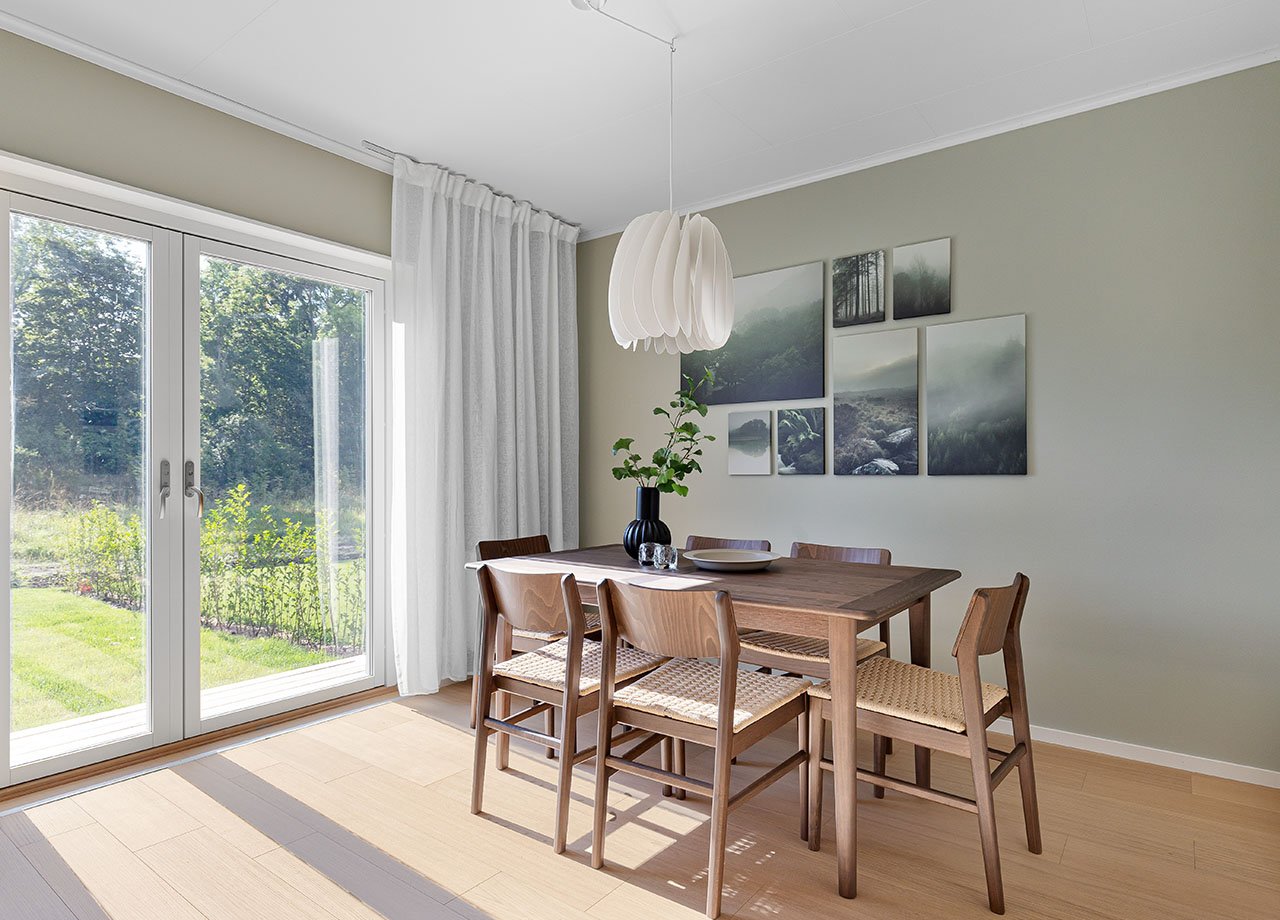 Vardagsrum med matplats och altandörrar i glas till uteplatsen i BoKlok radhus.