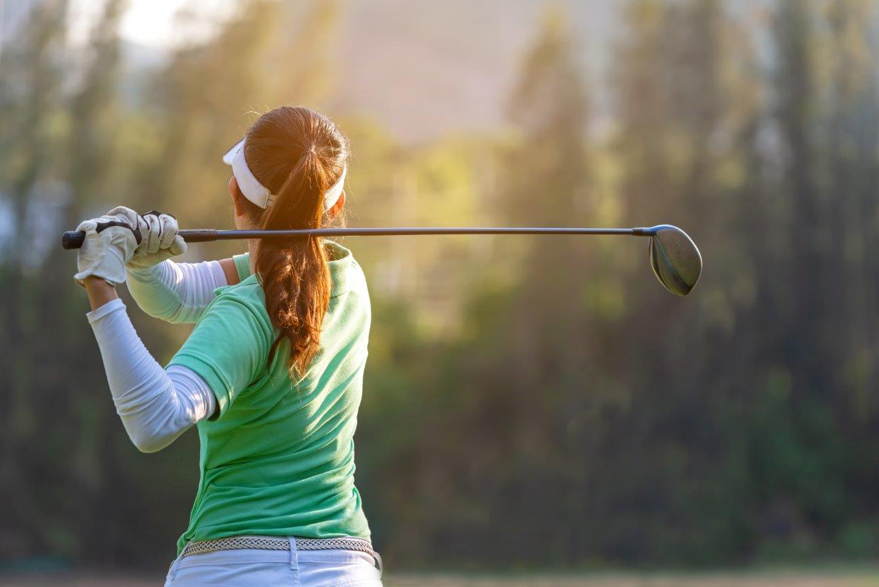 Kvinna spelar golf.