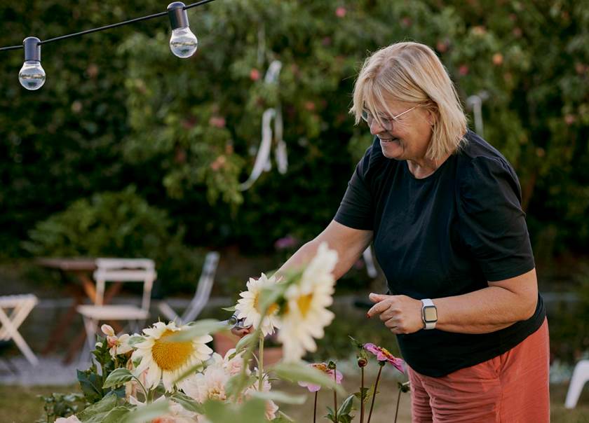Kvinna fixar med solrosor i sin trädgård.