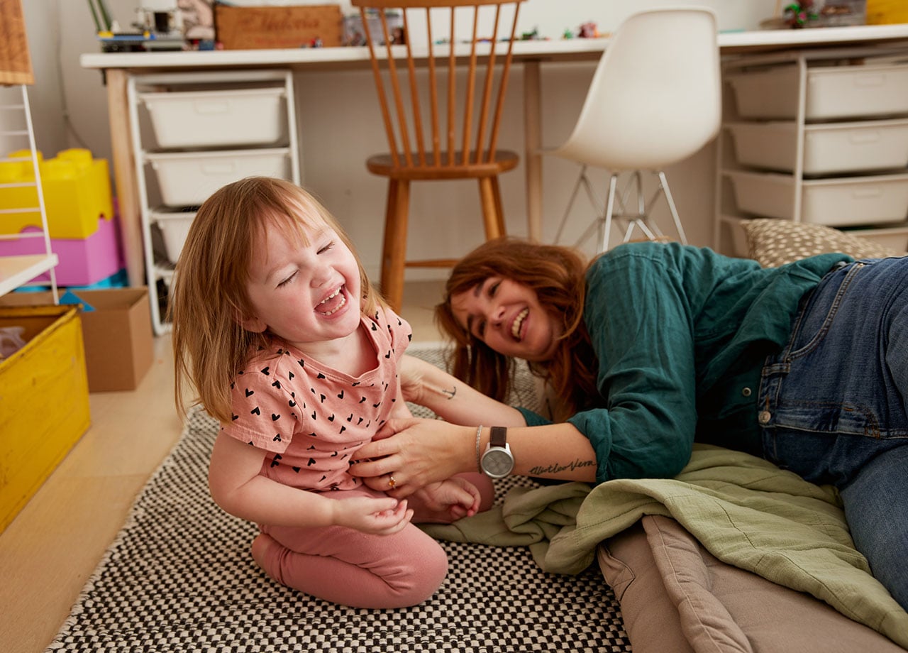 Flicka och mamma i trädgården som blåser såpbubblor 