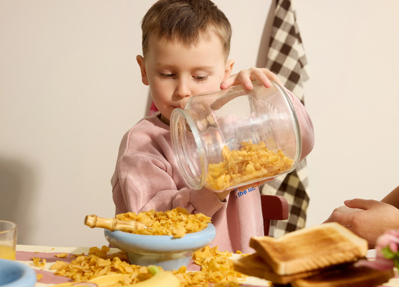 Flicka springer på skogsstig med sin mamma bakom sig.