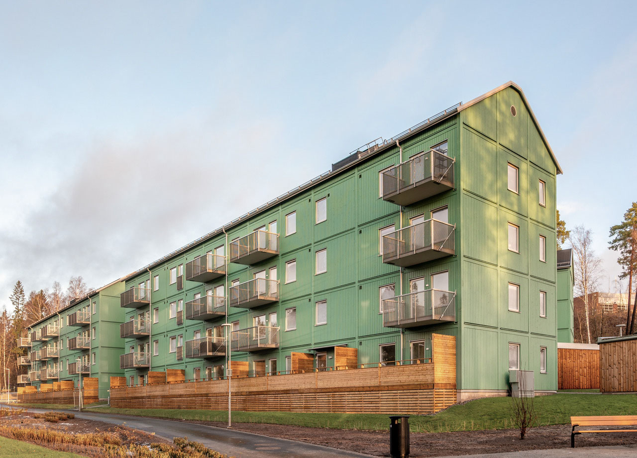 Foto på två gröna fyravåningshus med balkonger