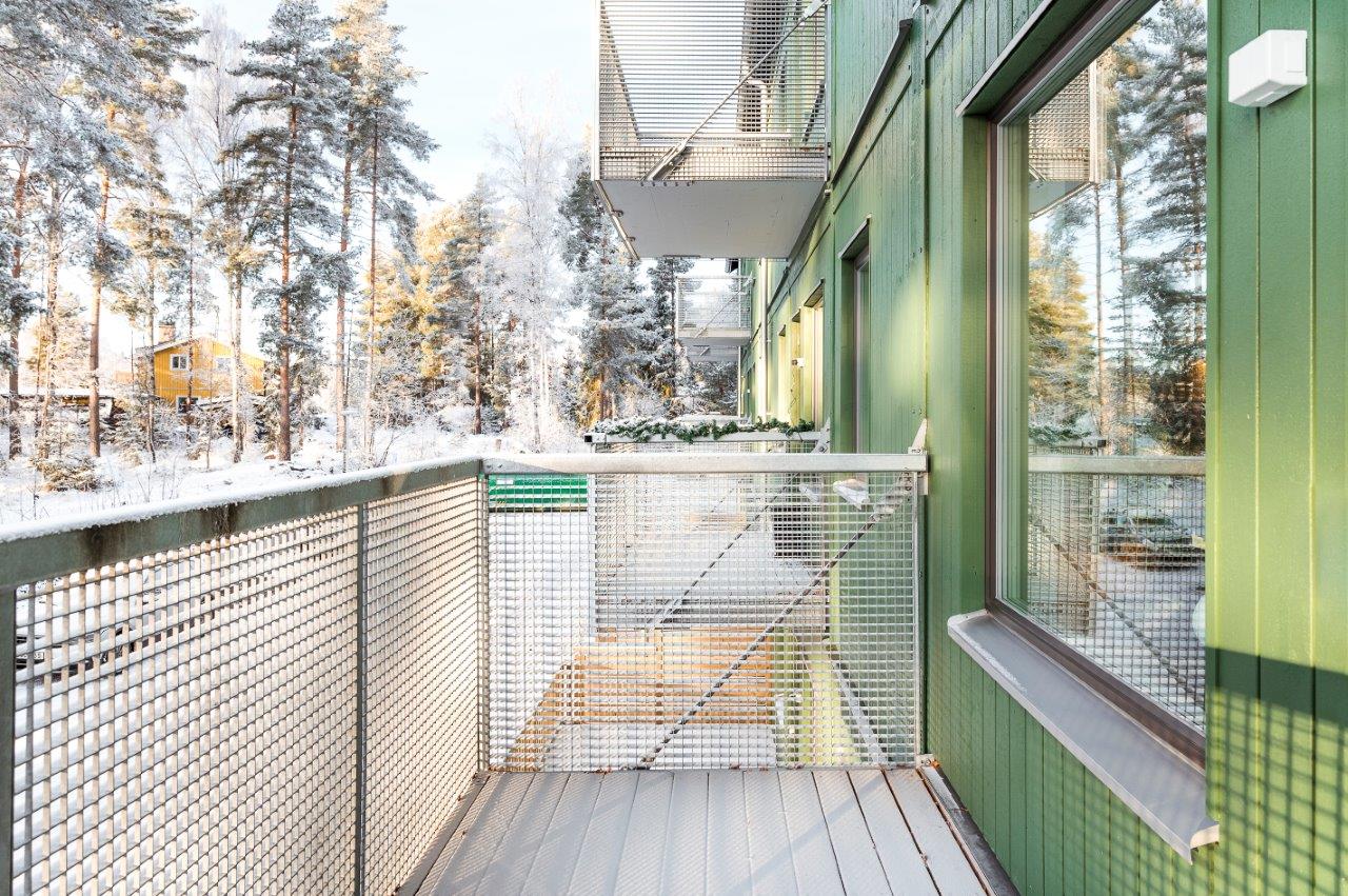 Balkong till BoKlok lägenhetshus med grön träfasad med snö.