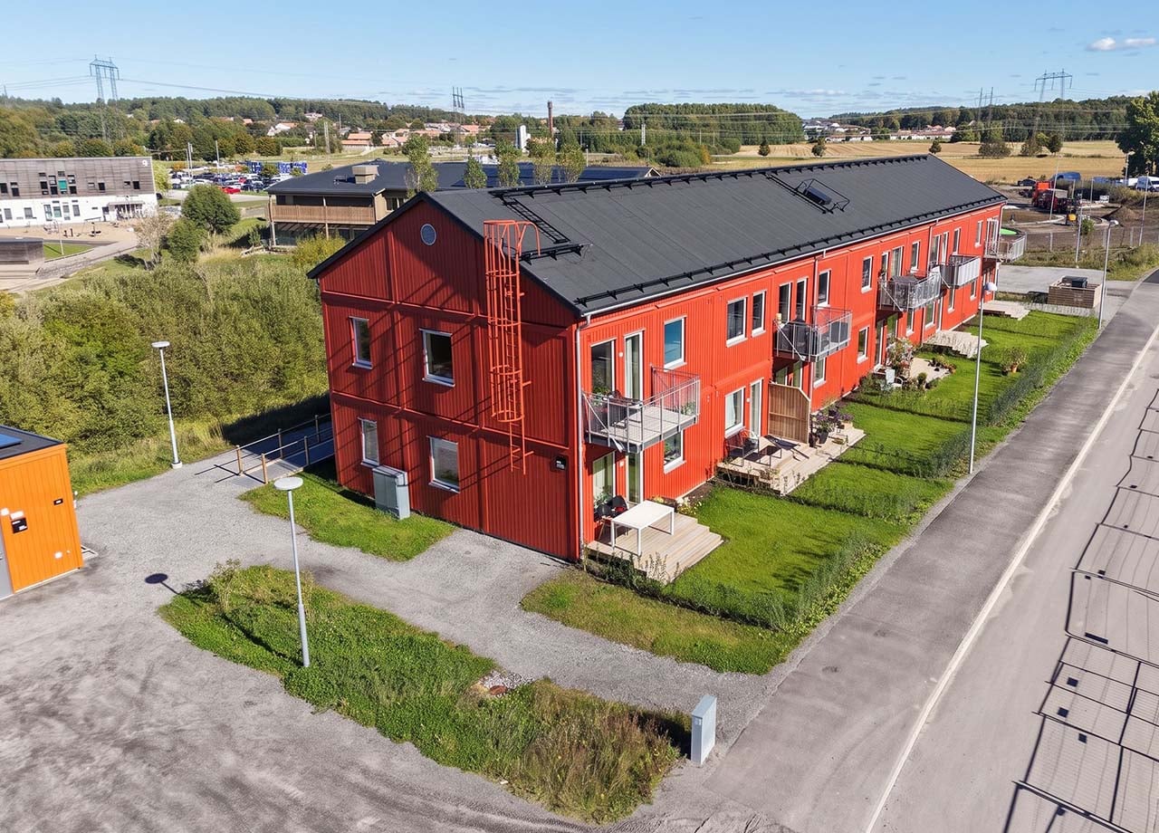 Flygfoto av altaner och balkonger till rött lägenhetshus i kvarteret BoKlok Klövern i Gråbo.