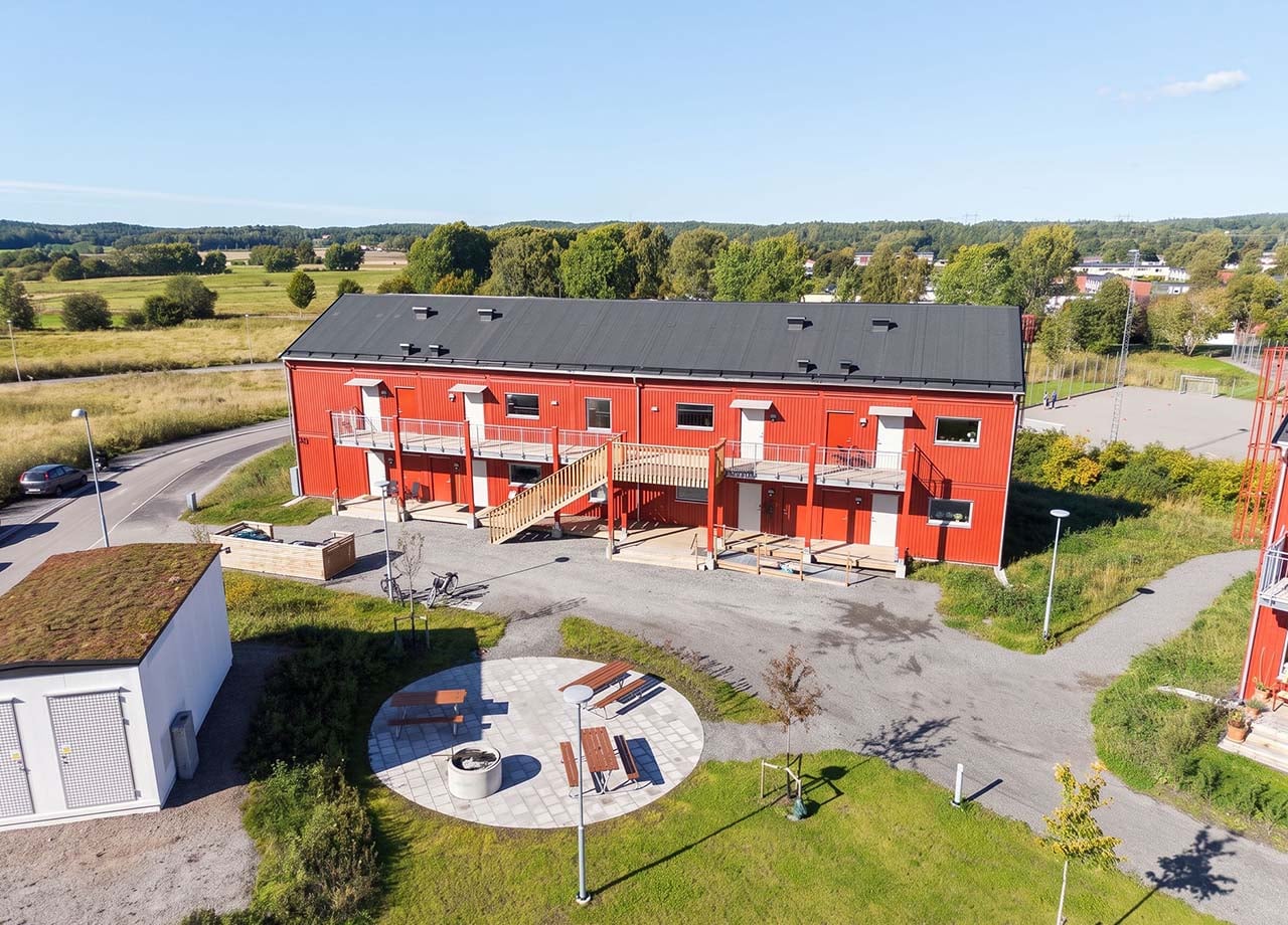 Flygfoto av loftgångssida med gemensamhetsyta med bänkar och bord i kvarteret BoKlok Klövern i Gråbo.