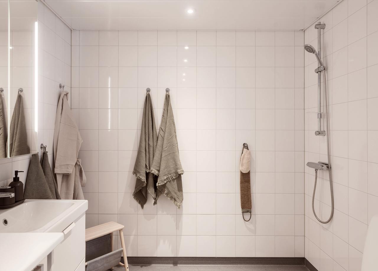 Badrum med vitt kakel och dusch i BoKlok lägenhet