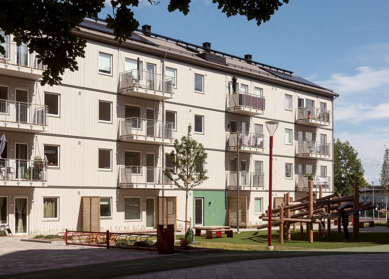 Lägenhetshus med fyra våningar med balkoger mot lekplats i BoKlok Rubinen i Bäckby Centrum i Västerås