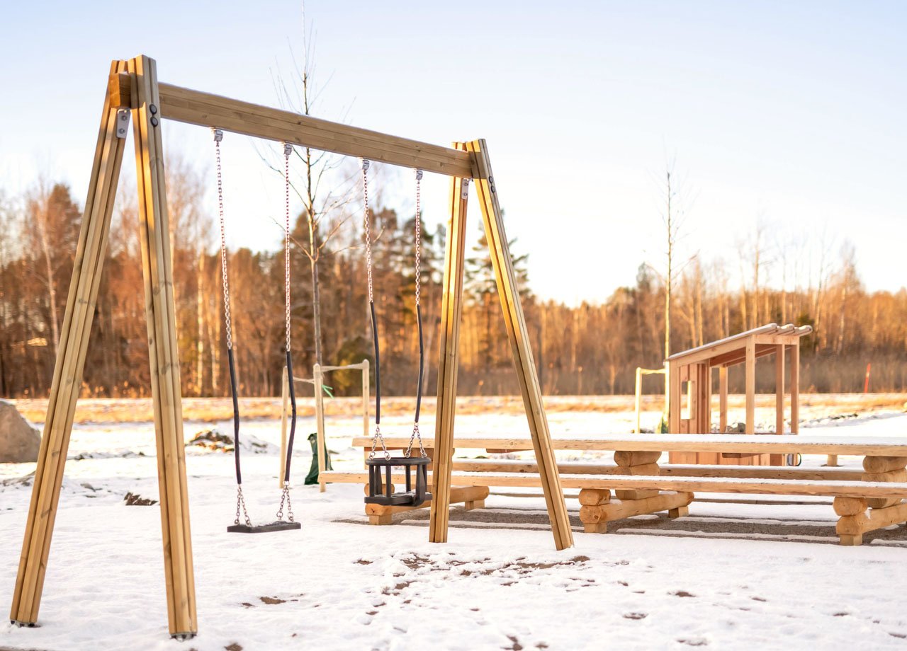 foto på lekplats i trä inbäddad i snö.