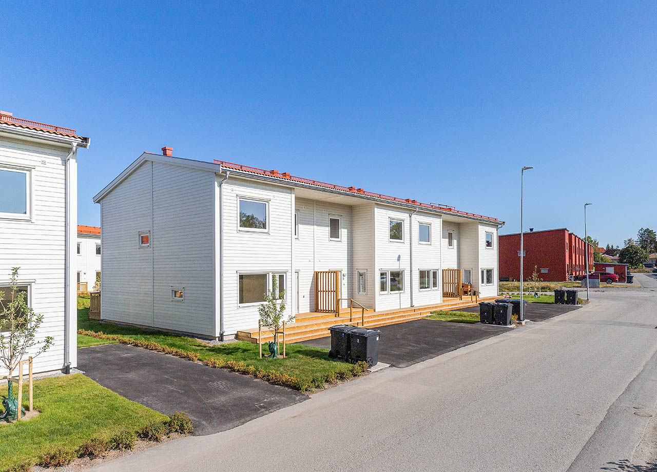 Entréer till vita radhus med uppfart en solig dag.