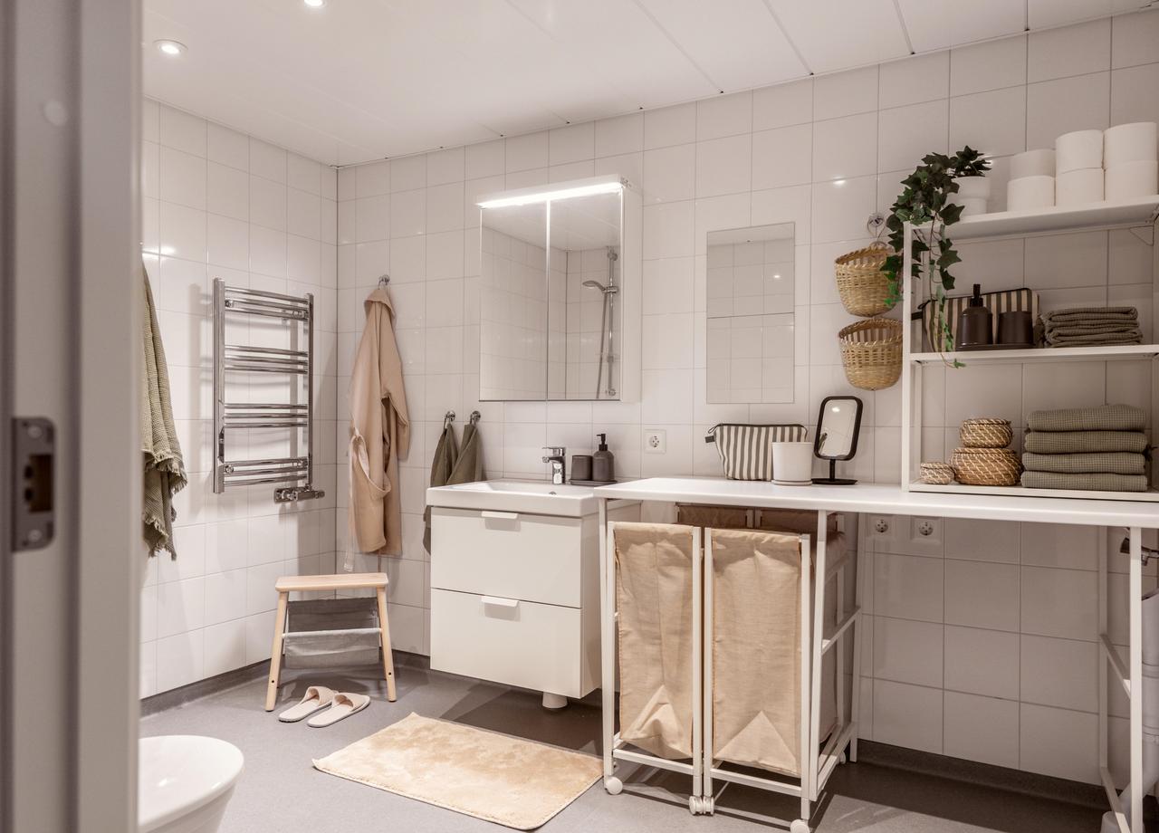 Foto på ett rymligt badrum med ljusgrå våtrumsmatta och vit inredning. 